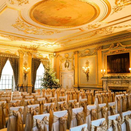 Wedding ceremony room with a Christmas tree and gold sash dressing chairs