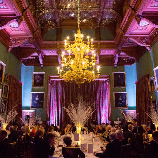 Majestic dinner setting at Knowsley Hall with purple mood lighting and huge gold chandelier occupying the room
