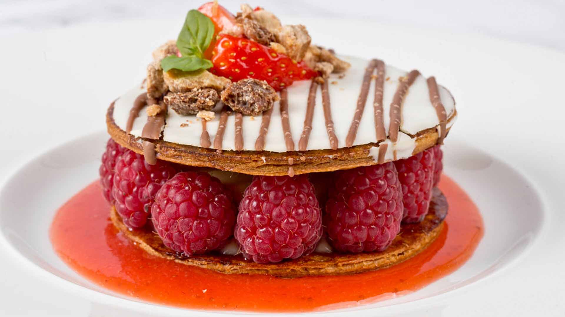 A picture of a dessert with pastry and fresh raspberries