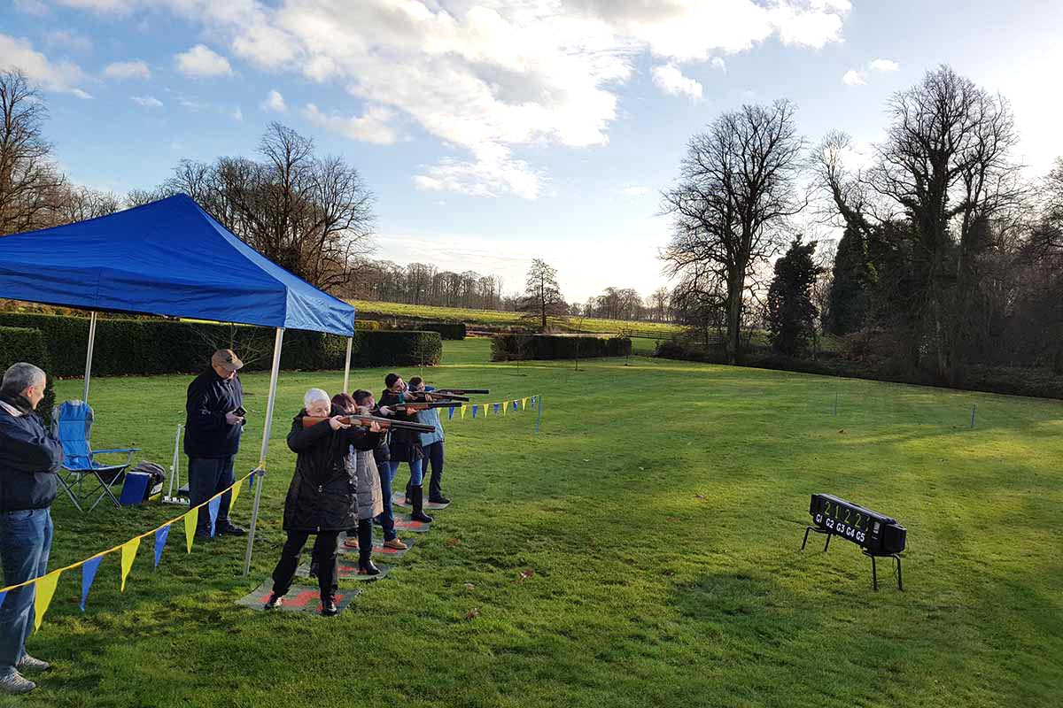 A group of people doing laser clay on the grounds of Knowsley Hall during a teambuilding activity day