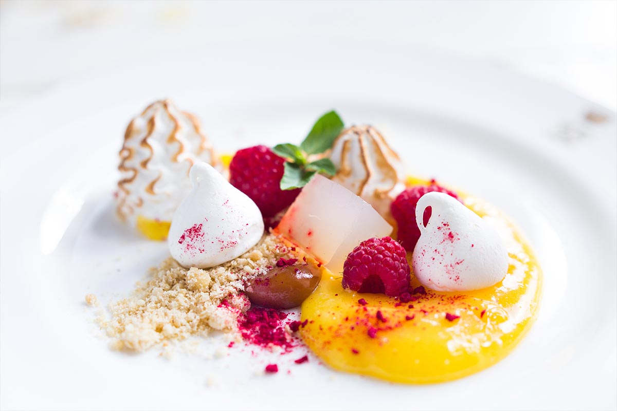 A plate of dessert with lemon, meringues and raspberry for corporate dining