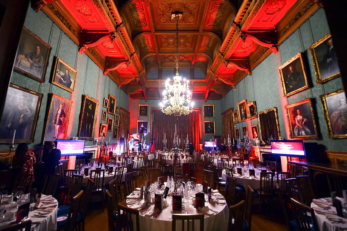 A huge dining room set for an awards dinner at Knowsley Hall with tables, chair, silver candelabras 