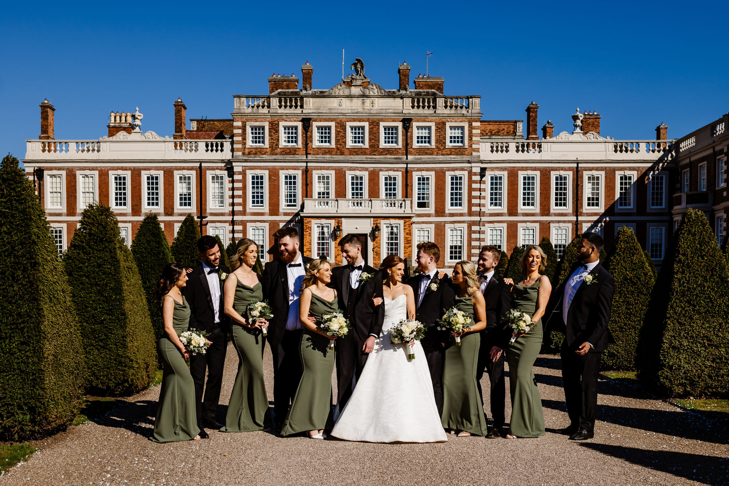 Bride & Groom on their wedding day with bridal team posing for photographs in the grounds of a stunning stately home